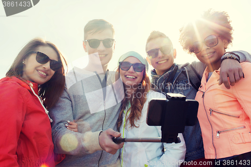 Image of friends taking selfie with smartphone on stick