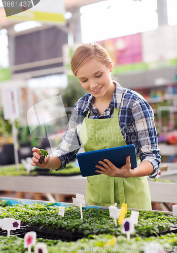 Image of happy woman with tablet pc in greenhouse