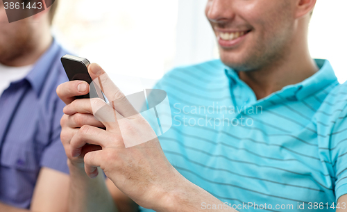 Image of close up of happy friends with smartphones at home