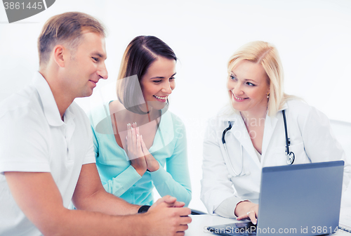 Image of doctor with patients looking at laptop