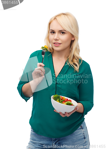 Image of smiling young woman eating vegetable salad