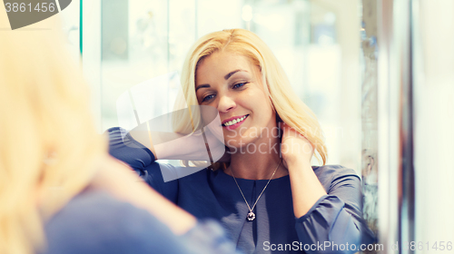 Image of happy woman choosing pendant at jewelry store