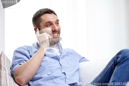 Image of happy man calling on smartphone at home