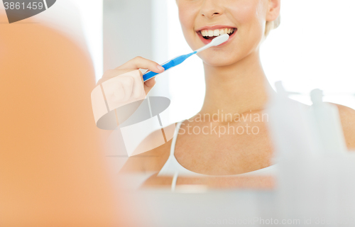 Image of woman with toothbrush cleaning teeth at bathroom