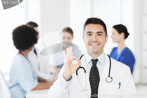 Image of happy doctor over group of medics at hospital