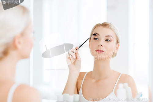 Image of woman brushing eyebrow with brush at bathroom