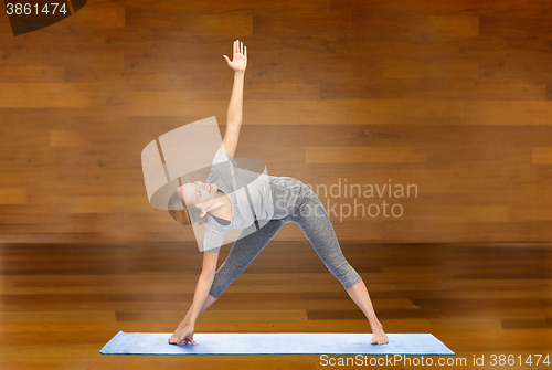 Image of woman making yoga triangle pose on mat