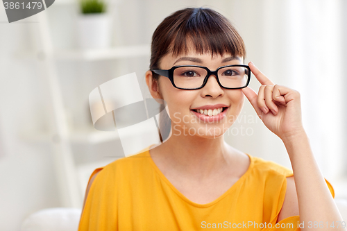 Image of happy asian young woman in glasses at home