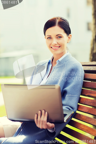 Image of smiling business woman with laptop in city