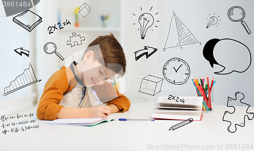 Image of smiling student boy writing to notebook at home