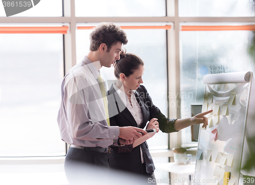 Image of young couple working on flip board at office