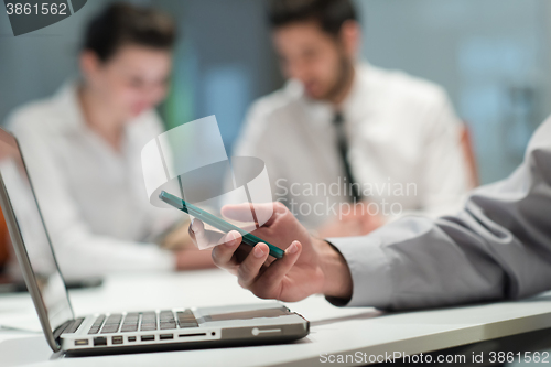 Image of close up of  businessman hands  using smart phone on meeting