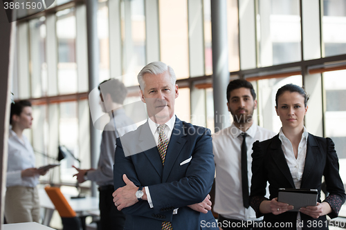 Image of portrait of senior businessman as leader  with group of people i
