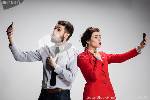Image of Business concept. The two young colleagues holding mobile phones on gray background