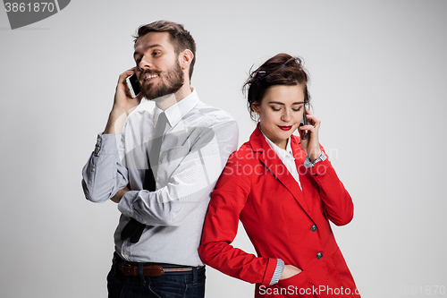 Image of Business concept. The two young colleagues holding mobile phones on gray background