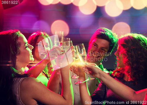 Image of smiling friends with glasses of champagne in club