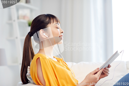 Image of happy asian woman with tablet pc and earphones