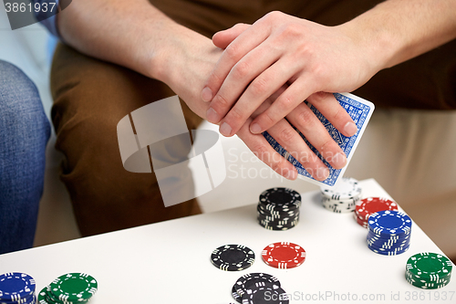 Image of close up of male hand with playing cards and chips