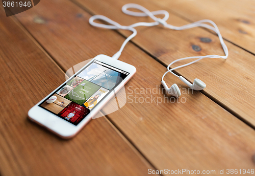 Image of close up of smartphone and earphones on wood