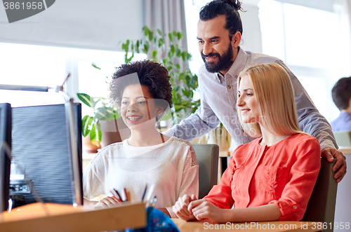 Image of happy creative team with computer in office