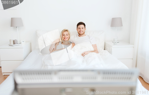 Image of happy couple lying in bed at home and watching tv