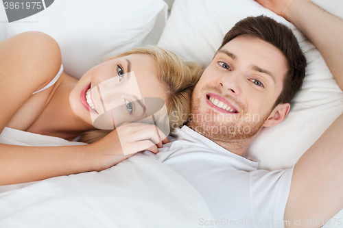 Image of happy couple lying in bed at home