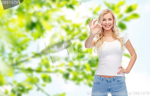 Image of happy young woman in white t-shirt showing ok sign