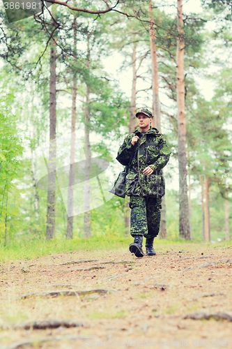 Image of young soldier or hunter with gun in forest