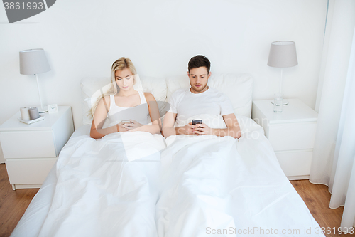 Image of couple with smartphones in bed