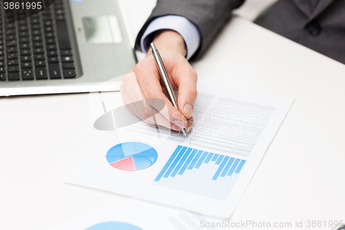 Image of close up of businessman hand with charts in office