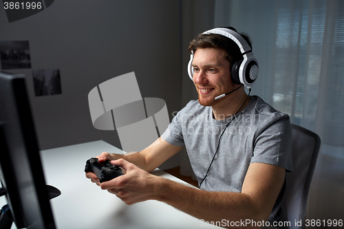 Image of man in headset playing computer video game at home