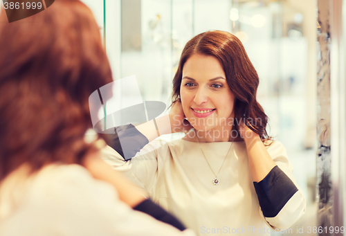 Image of happy woman choosing pendant at jewelry store