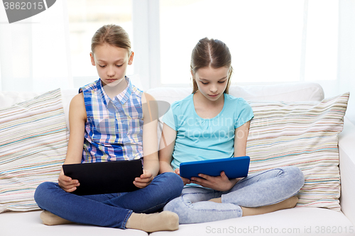 Image of girls with tablet pc sitting on sofa at home