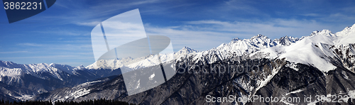 Image of Panoramic view on snowy mountains in sun windy day