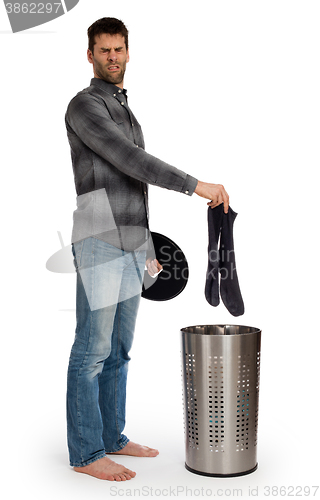 Image of Young man putting dirty socks in a laundry basket