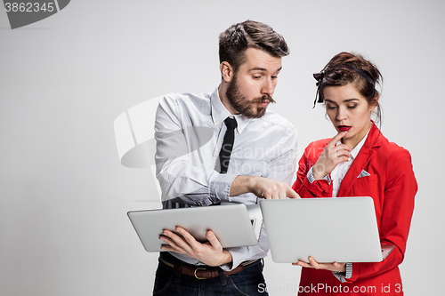 Image of The young businessman and businesswoman with laptops  communicating on gray background