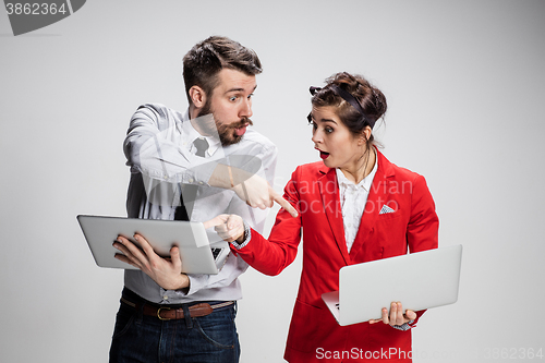 Image of The young businessman and businesswoman with laptops  communicating on gray background