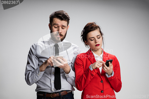 Image of Business concept. The two young colleagues holding mobile phones on gray background