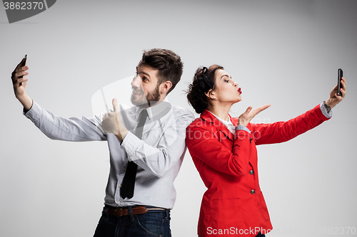 Image of Business concept. The two young colleagues holding mobile phones on gray background