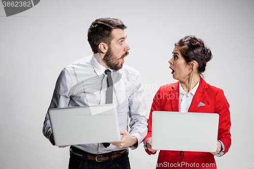 Image of The young businessman and businesswoman with laptops  communicating on gray background