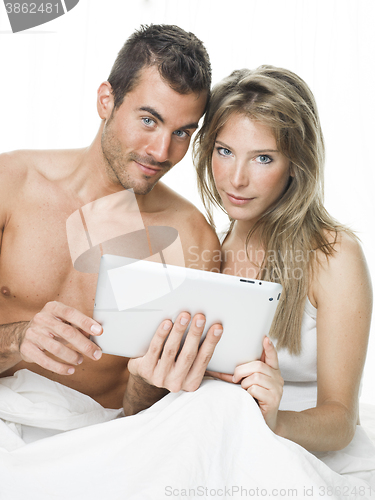 Image of attractive couple watching things in a tablet