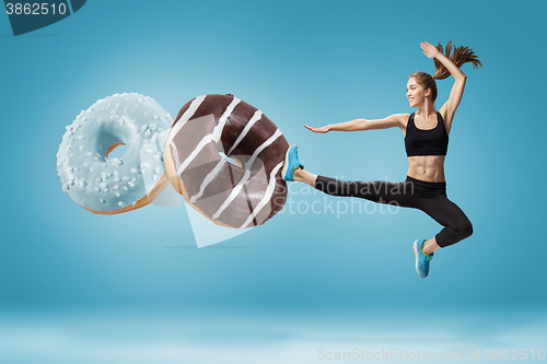 Image of Fit young woman fighting off bad food on a blue background