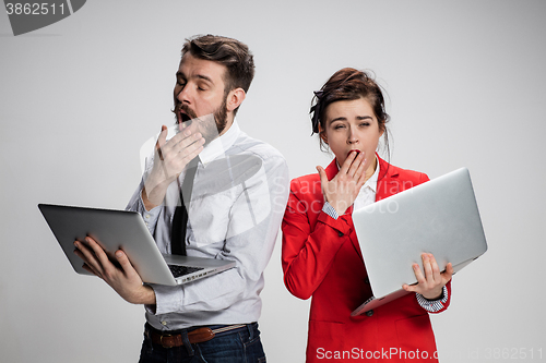 Image of The young businessman and businesswoman with laptops on gray background