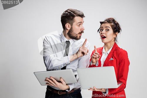 Image of The young businessman and businesswoman with laptops  communicating on gray background