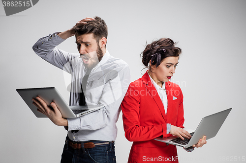 Image of The young businessman and businesswoman with laptops  communicating on gray background