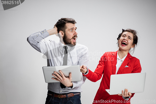 Image of The young businessman and businesswoman with laptops smiling on gray background