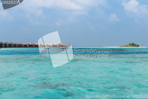 Image of bungalow huts in sea water on exotic resort beach