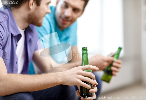 Image of close up of male friends drinking beer at home