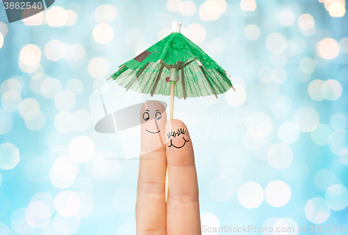 Image of close up of two fingers with cocktail umbrella