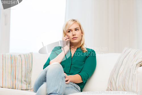 Image of young woman calling on smartphone at home